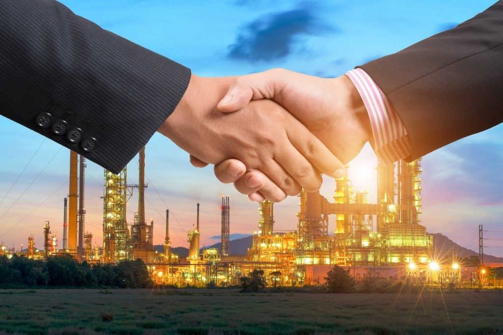 Business handshake in front of a refinery